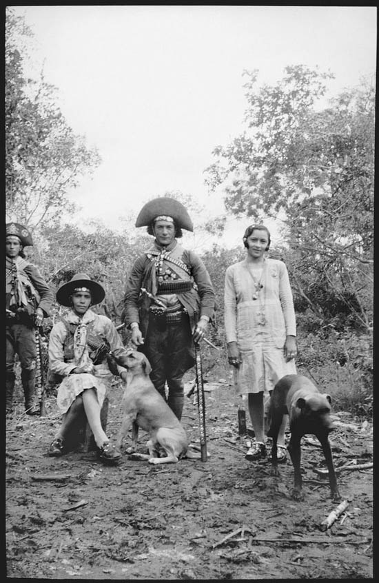 Nenê acariciando o cão Ligeiro, seu companheiro Luís Pedro e Maria Bonita com o cão Guarani. Ao fundo o cangaceiro Juriti., 1936. Foto de Benjamim Abrahão