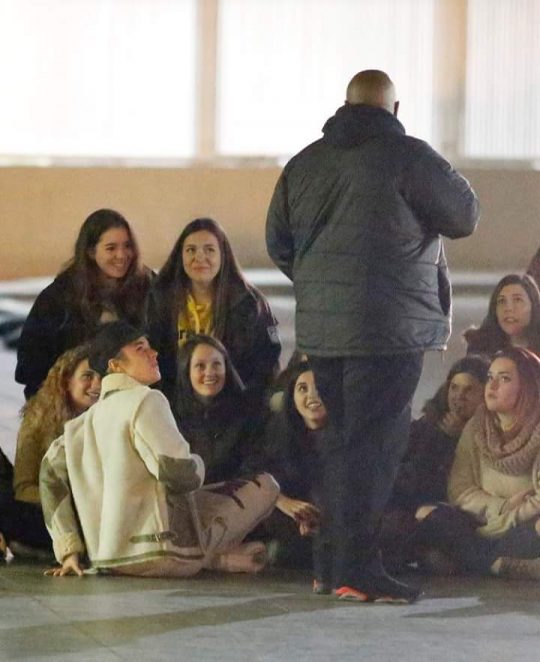Justin Bieber, sentado, de branco, com fãs no aeroporto de Barcelona. Foto: Reprodução/Twitter